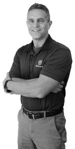 A black and white image of Jeff Johnson from the waist up crossing his arms while smiling and wearing a striped Power/mation polo shirt